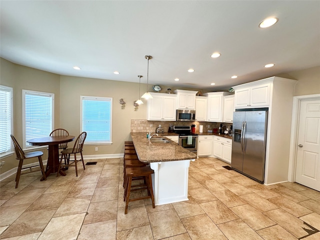 kitchen featuring stainless steel appliances, tasteful backsplash, kitchen peninsula, dark stone countertops, and pendant lighting