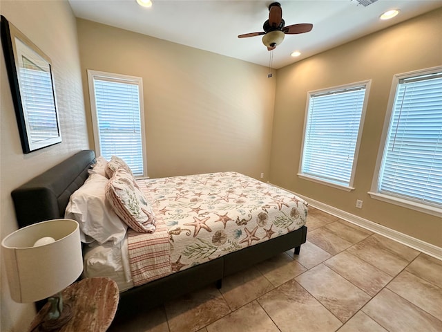 bedroom with ceiling fan, light tile patterned flooring, and multiple windows