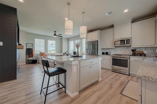 7659 Green Bulrush Way, Katy, TX 77493 - kitchen featuring stainless steel appliances, open floor plan, a kitchen island, light wood finished floors, and tasteful backsplash