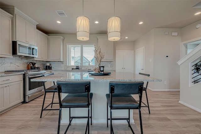 7659 Green Bulrush Way, Katy, TX 77493 - kitchen with appliances with stainless steel finishes, a center island, backsplash, a kitchen breakfast bar, and recessed lighting