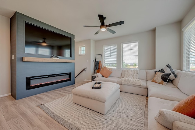 living room featuring ceiling fan, a fireplace, and light hardwood / wood-style flooring