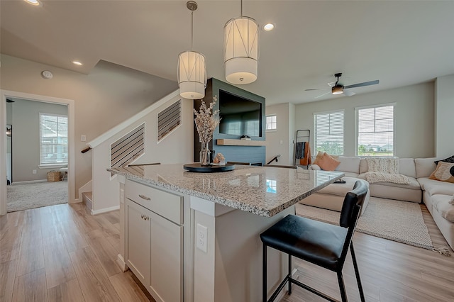 7659 Green Bulrush Way, Katy, TX 77493 - kitchen featuring open floor plan, ceiling fan, light wood-style floors, light stone countertops, and decorative light fixtures