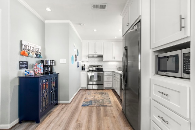 kitchen featuring tasteful backsplash, ornamental molding, stainless steel appliances, white cabinetry, and light hardwood / wood-style floors