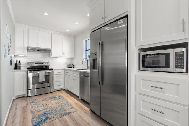 kitchen featuring stainless steel appliances, sink, light hardwood / wood-style flooring, crown molding, and white cabinets