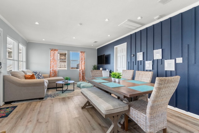 dining space with light wood-type flooring, a healthy amount of sunlight, and crown molding