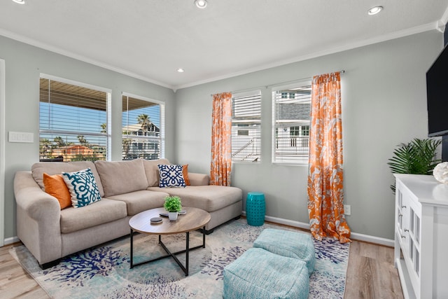 living room with ornamental molding, a wealth of natural light, and light hardwood / wood-style floors