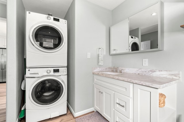 washroom featuring stacked washer and dryer, sink, and light hardwood / wood-style floors