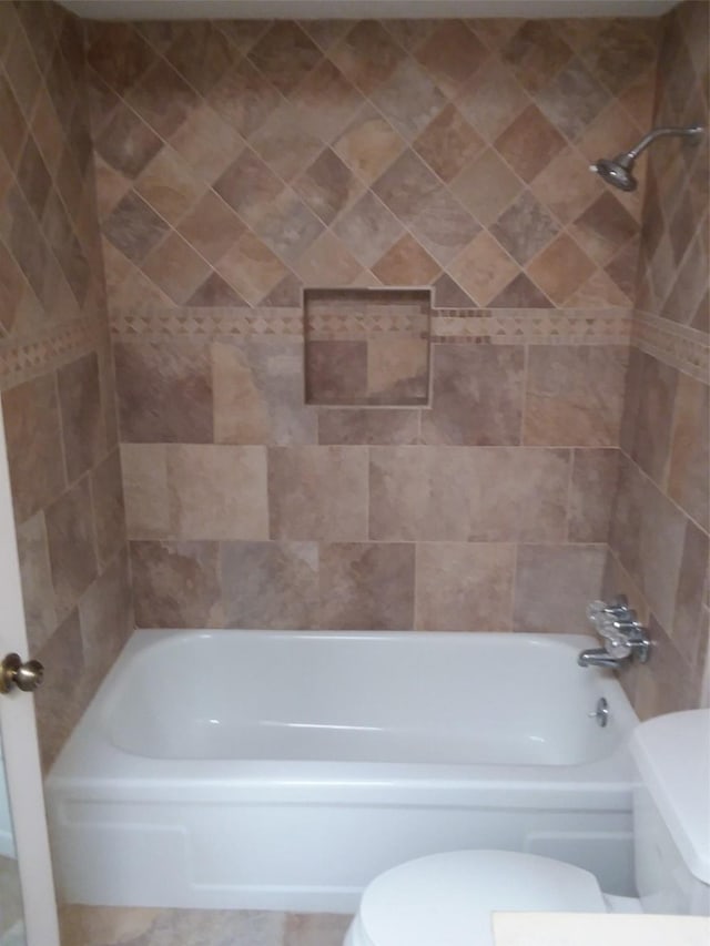 bathroom with toilet and tiled shower / bath