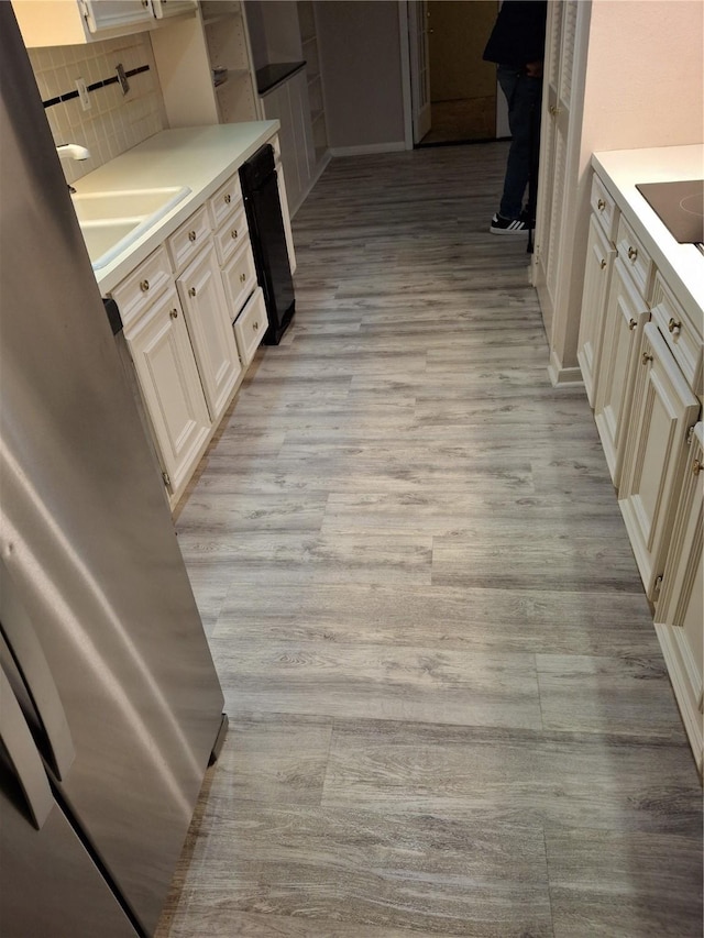 kitchen featuring dishwasher, sink, backsplash, cream cabinets, and light hardwood / wood-style floors