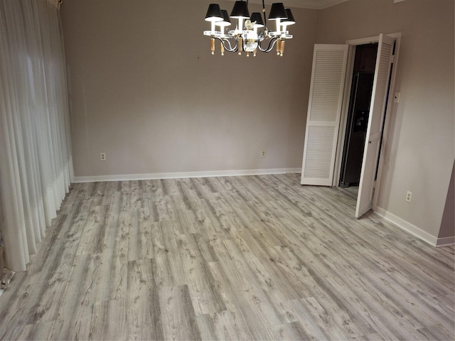 empty room featuring light hardwood / wood-style floors and an inviting chandelier