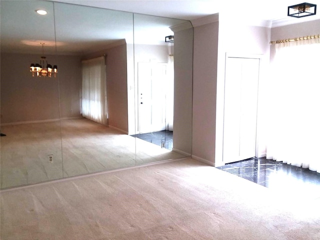 empty room with carpet flooring, crown molding, and a chandelier