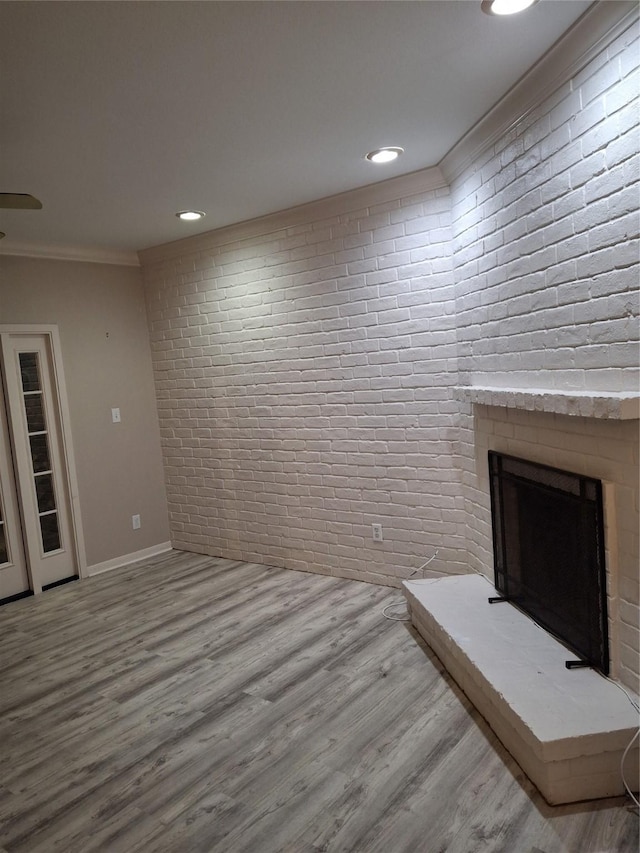 interior space with hardwood / wood-style flooring, ornamental molding, a fireplace, and brick wall