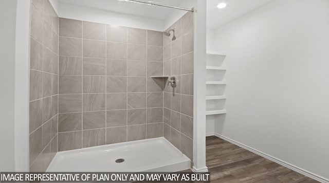 bathroom with hardwood / wood-style flooring and a tile shower