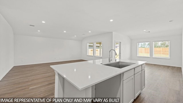 kitchen with white cabinets, sink, a kitchen island with sink, and light hardwood / wood-style flooring