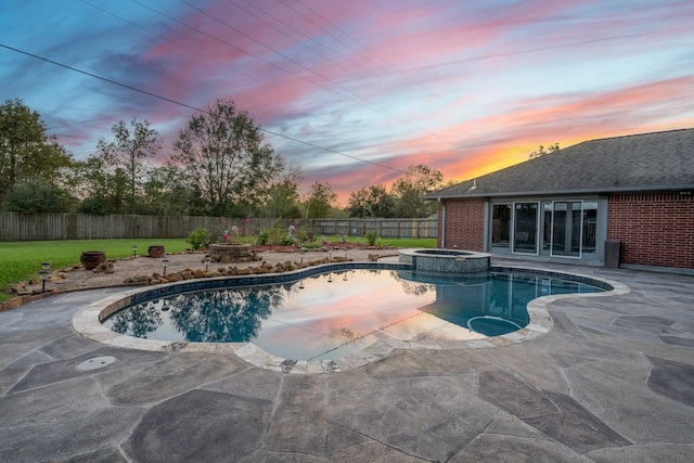 pool at dusk with an in ground hot tub and a patio