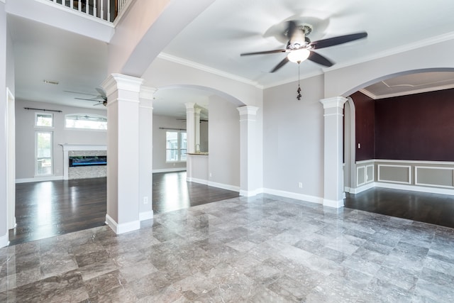 spare room with ornate columns, ceiling fan, a high end fireplace, and crown molding