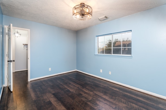 spare room featuring dark wood-type flooring and a textured ceiling