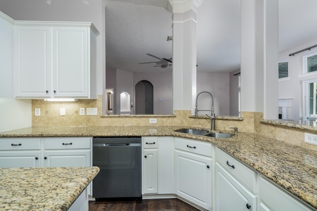 kitchen featuring sink, dishwashing machine, light stone counters, and white cabinets