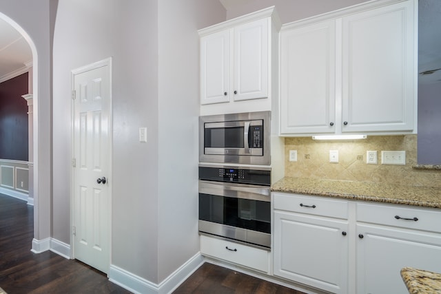 kitchen featuring light stone counters, white cabinets, appliances with stainless steel finishes, and dark hardwood / wood-style floors