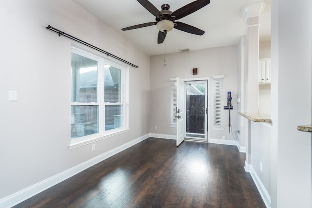 entrance foyer with ceiling fan, ornate columns, and dark wood-type flooring