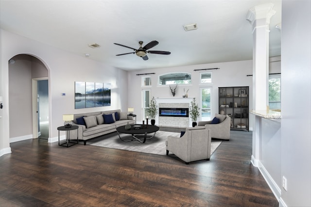 living room featuring ceiling fan, dark wood-type flooring, a wealth of natural light, and decorative columns