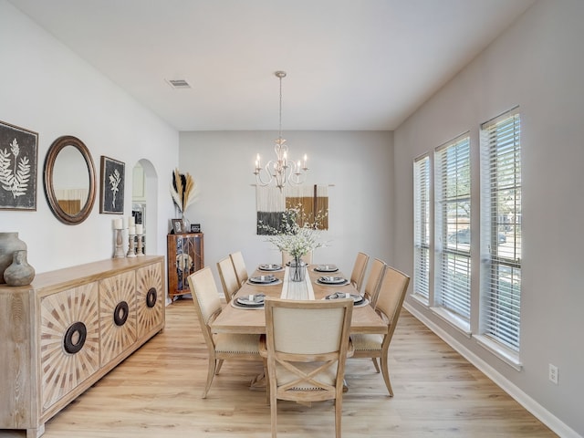 dining space with light wood-type flooring and a notable chandelier