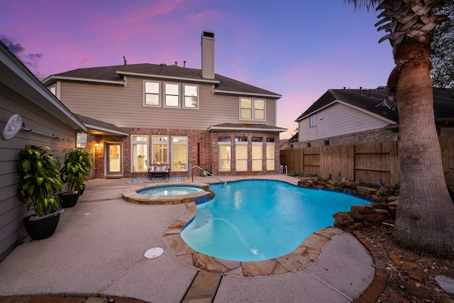 pool at dusk with a patio and an in ground hot tub