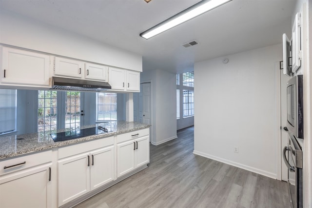 kitchen with light hardwood / wood-style flooring, white cabinetry, plenty of natural light, and black electric stovetop