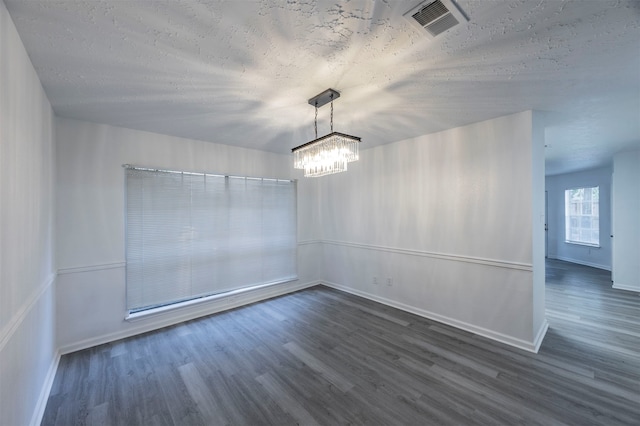 unfurnished dining area with a chandelier, a textured ceiling, and dark hardwood / wood-style floors