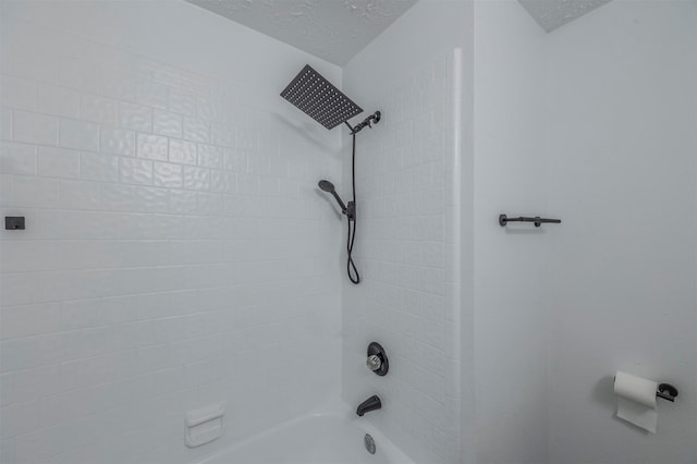 room details with tiled shower / bath and a textured ceiling