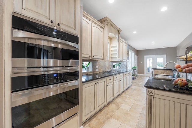 kitchen featuring light brown cabinets, sink, dark stone countertops, tasteful backsplash, and stainless steel appliances