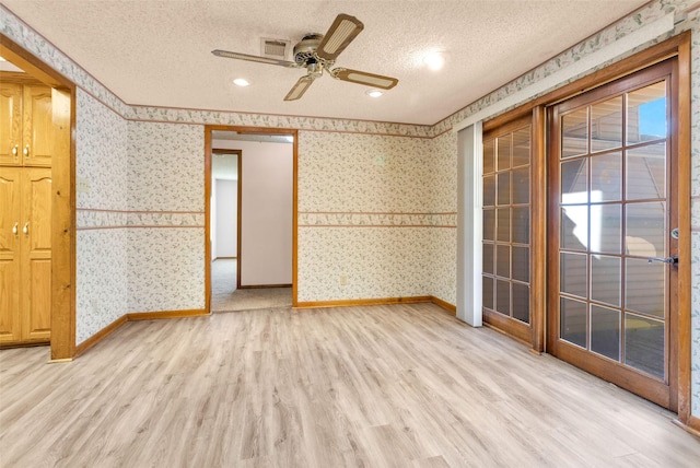 empty room with a textured ceiling, ceiling fan, and light hardwood / wood-style floors