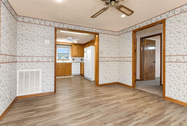 unfurnished living room with ceiling fan, a textured ceiling, and light hardwood / wood-style floors