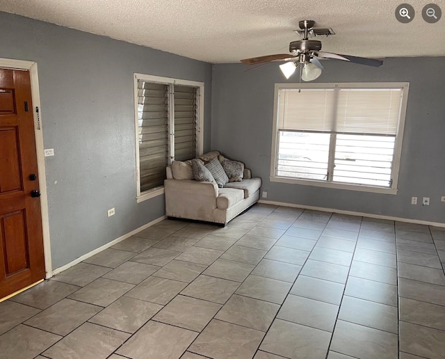 interior space with a textured ceiling, ceiling fan, and light tile patterned floors