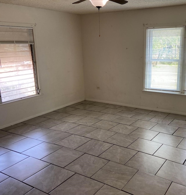 spare room with ceiling fan, a textured ceiling, and light tile patterned floors