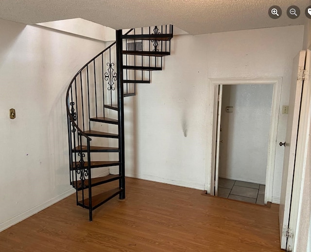 stairs featuring wood-type flooring and a textured ceiling