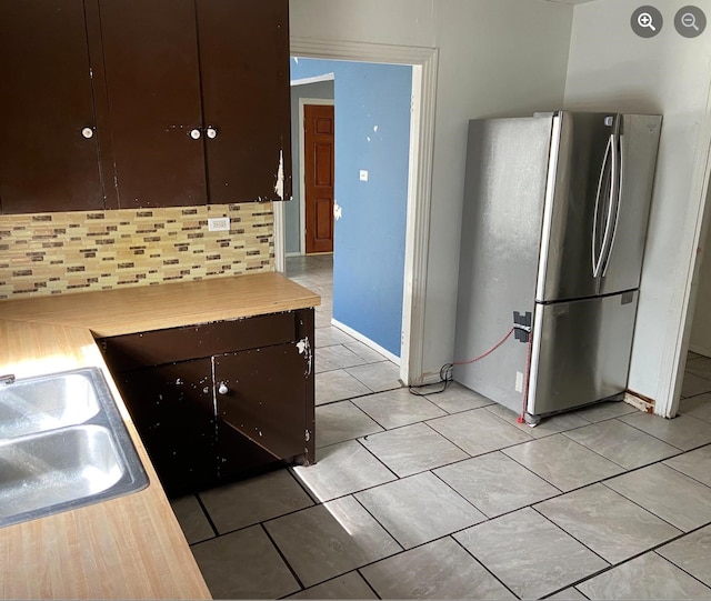 kitchen with tasteful backsplash, dark brown cabinets, sink, and stainless steel refrigerator