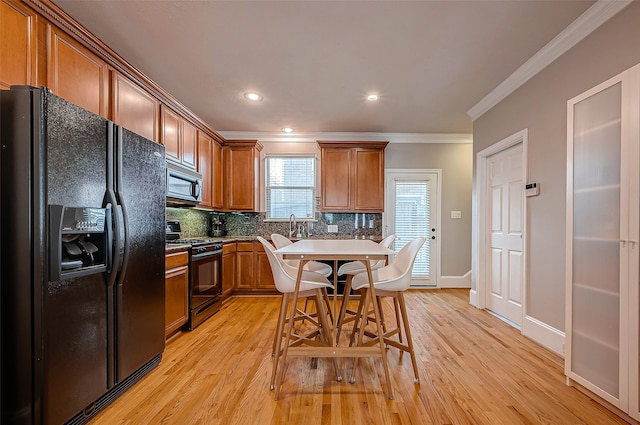 kitchen featuring ornamental molding, light hardwood / wood-style flooring, black appliances, and backsplash