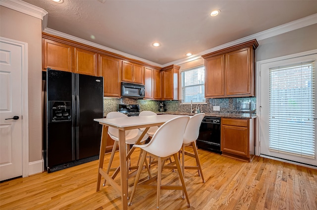 kitchen with ornamental molding, black appliances, decorative backsplash, and light hardwood / wood-style flooring