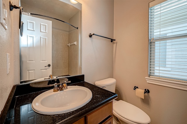 bathroom with vanity, toilet, and a tile shower