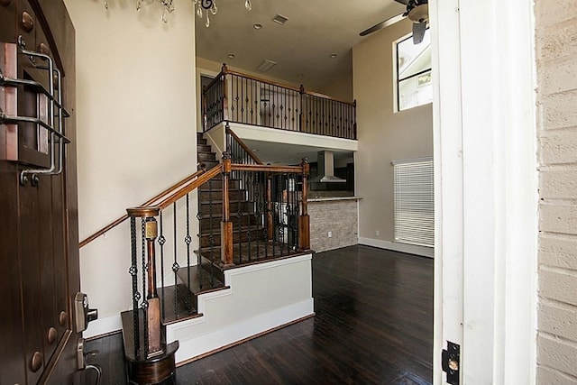 stairs with wood-type flooring, ceiling fan, and a high ceiling