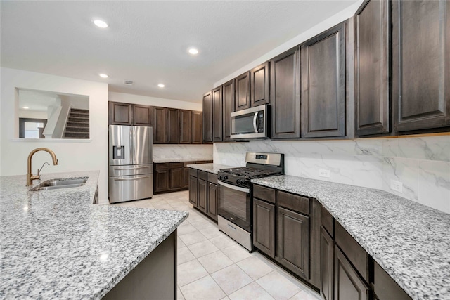 kitchen featuring dark brown cabinets, appliances with stainless steel finishes, sink, and light stone counters