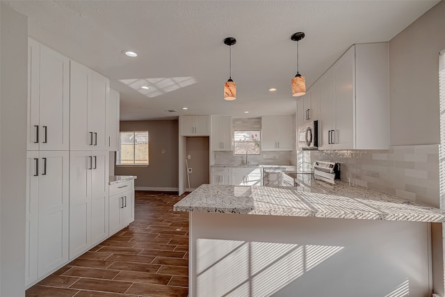 kitchen with stainless steel appliances, dark hardwood / wood-style flooring, white cabinets, pendant lighting, and decorative backsplash