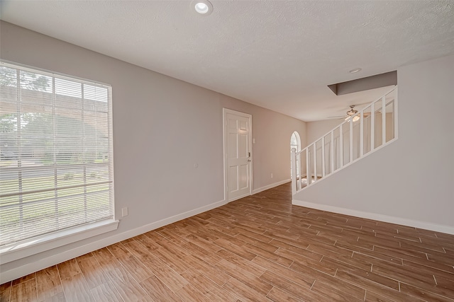 empty room featuring a textured ceiling, wood-type flooring, and a healthy amount of sunlight