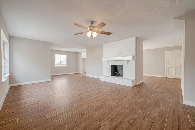 unfurnished living room with a fireplace, hardwood / wood-style flooring, ceiling fan, and a textured ceiling