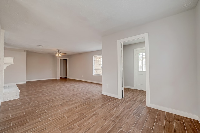 unfurnished living room featuring a brick fireplace, light wood-type flooring, and ceiling fan