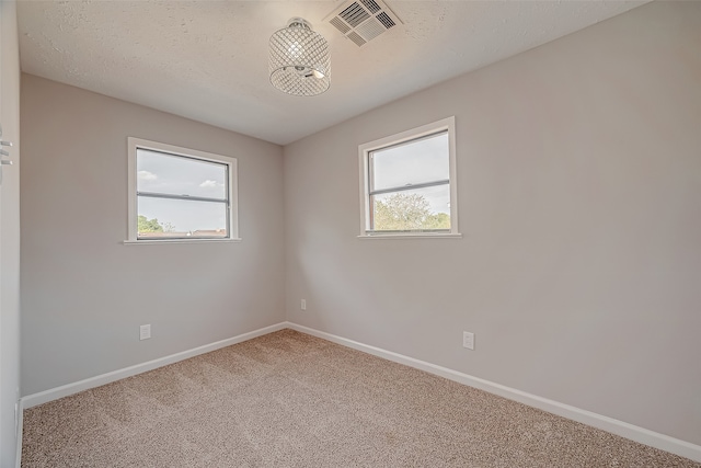 empty room featuring a wealth of natural light, an inviting chandelier, and carpet floors