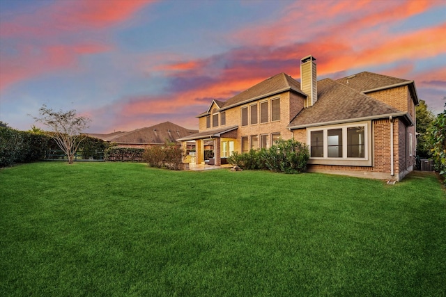 back house at dusk featuring a yard