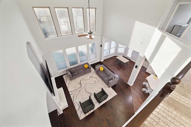 living room featuring a towering ceiling, dark hardwood / wood-style floors, and ceiling fan