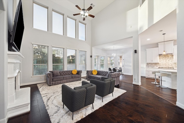 living room featuring a high ceiling, dark hardwood / wood-style floors, and ceiling fan with notable chandelier